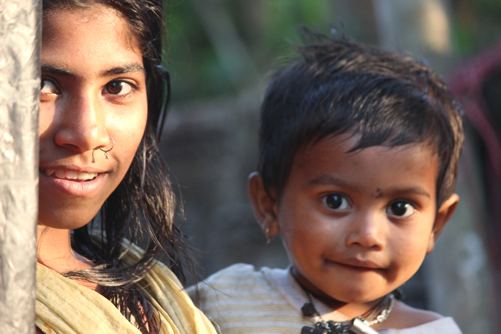 Girl with a toddler on her hip in Sreemangal, Bangladesh, by Tharik Hussain.