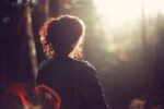 woman looking out at forest with bokeh