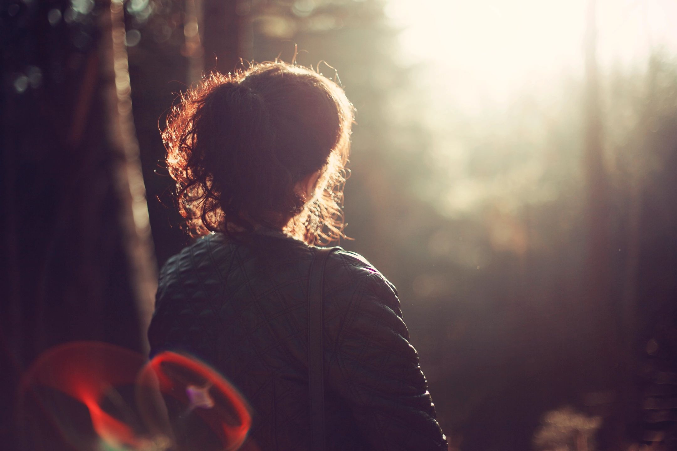 woman looking out at forest with bokeh