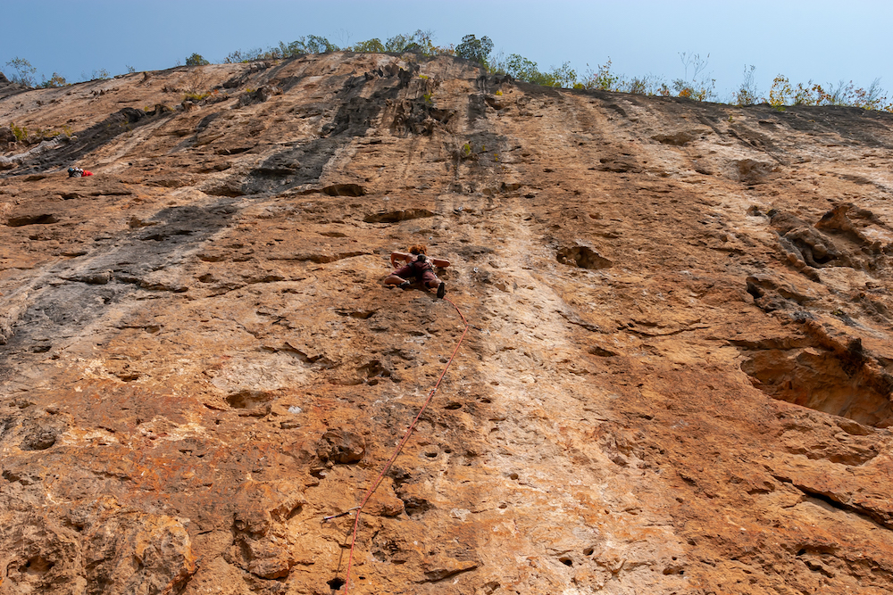 Climbers tackling a vertical rock face, hundreds of metres high, near the Silver Cave show cave in China